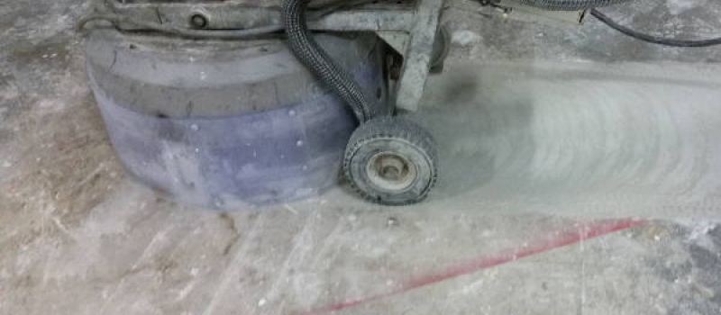 Vervuilde beton schuren Een licht vervuilde betonvloer waarop wij zojuist zijn begonnen met het afschuren van de vervuiling bestaande uit verfresten e.d.